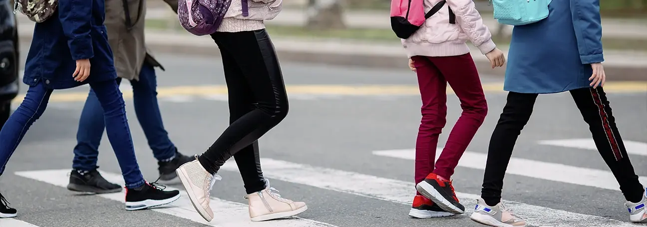 [Schoolchildren crossing a road at a crosswalk]