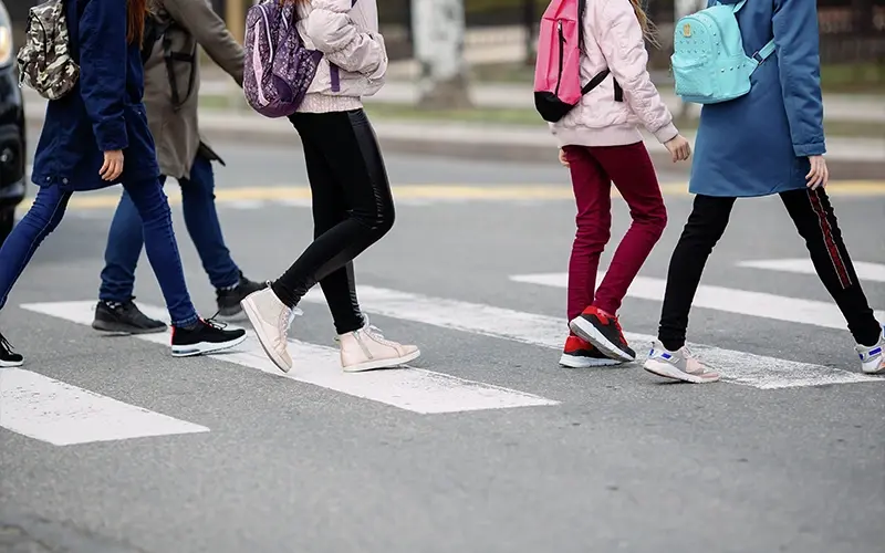 [Schoolchildren crossing a road at a crosswalk]