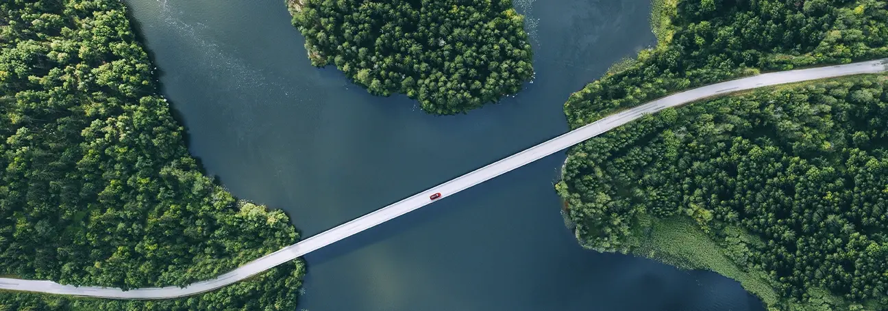 [Vogelperspektive rotes Fahrzeug auf Brücke über Fluss]