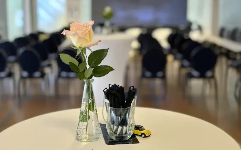 [Seminarraum Stehtisch mit Rose, Kugelschreiber, Spielzeugauto]